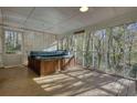 Enclosed sunroom featuring a hot tub, lattice, screens, and views of the surrounding trees at 2194 Highway 20 E., Mcdonough, GA 30252