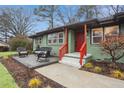 Inviting front porch features a stylish seating area with a red railing for a pop of color at 1322 Elmhurst Circle Se Cir, Atlanta, GA 30316