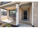 Inviting front porch of a brick home with a bench, dark door and beautiful landscaping at 1809 Hanwoo Ln, Powder Springs, GA 30127