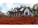 Eye-catching farmhouse featuring a covered porch with wood columns, contrasted by its white and black design at 472 Price Rd, Carrollton, GA 30116