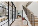 Bright foyer with a staircase, hardwood floors, and black framed glass doors and windows at 6455 Scott Valley Rd, Sandy Springs, GA 30328