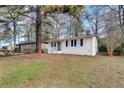 A small white-painted bungalow-style house with dark shutters sits on a green lawn beneath mature trees at 895 Mercury Nw Dr, Atlanta, GA 30331
