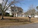 Spacious front yard featuring a two-story home with a two-car garage and mature trees at 158 Weatherstone Dr, Woodstock, GA 30188