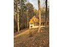 View of a cozy two-story home, surrounded by mature trees and natural landscape, bathed in sunlight at 110 Casa Domain Ct, South Fulton, GA 30349