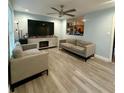 Living room featuring a fireplace, mounted TV, ceiling fan, and new wood floors at 172 Scarsdale Dr, Riverdale, GA 30274