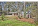 Brick home with covered carport surrounded by mature trees and green lawn at 3339 Brenda Ln, Lithia Springs, GA 30122