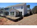 View of the home's rear exterior with a sunroom and unfinished landscaping at 1985 William Glen St, Dacula, GA 30019