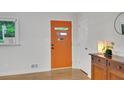Clean bright entryway with orange door, hardwood floors, and side table at 615 Spruce Dr, Pine Lake, GA 30072