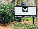 Street view of the Mount Vernon Village community sign with address set amongst lush greenery at 475 Mount Vernon Ne Hwy # C230, Sandy Springs, GA 30328