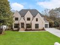 Attractive two-story house with manicured lawn, modern dark framed windows, and side entry two car garage at 4895 Lansbury Dr, Atlanta, GA 30342