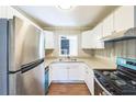 Galley kitchen featuring stainless steel appliances, stone countertops, white cabinets, and wood-look flooring at 5063 White Sw Blvd, Mableton, GA 30126