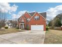Charming brick home with a two-car garage, landscaped yard, and long concrete driveway at 114 Highgrove Pl, Mcdonough, GA 30253