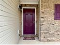 A brick facade and vibrant purple door with welcome mat create an inviting entryway at 46 Darbys Crossing Ct, Hiram, GA 30141