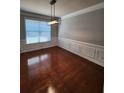 Formal dining room featuring hardwood floors, wainscoting, a modern chandelier, and ample natural light at 2571 Royston Dr, Duluth, GA 30097