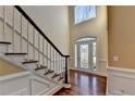 Elegant foyer features gleaming hardwood floors, stairs with white spindles and stained banister at 1921 Harvest Way, Loganville, GA 30052