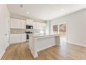 Well-lit kitchen featuring a large island, modern appliances, granite counters, white cabinets, and sliding doors to the exterior at 5526 Rosehall Pl, Atlanta, GA 30349