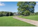 Long driveway leads to a traditional two-story home with a lush lawn and mature trees at 1525 Thomas Rd, Canton, GA 30115