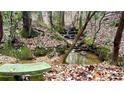 Serene backyard setting with a gentle stream and a tranquil stone bench surrounded by lush greenery at 7460 Highway 101, Rockmart, GA 30153