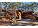 A rustic home featuring wood and stone elements, surrounded by lush greenery and a private driveway at 2513 Overlake Ln, Stockbridge, GA 30281
