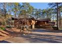 Charming exterior showcasing wood siding, stone foundation, mature trees, and a winding driveway at 2513 Overlake Ln, Stockbridge, GA 30281