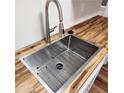 Close up of a new stainless steel kitchen sink with modern faucet and butcher block countertop at 2413 Charleston Pointe Ct, Atlanta, GA 30316