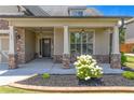 Close-up view of a home's inviting front porch featuring stone pillars and a landscaped flower bed at 145 Meadow Branch Ln, Dallas, GA 30157