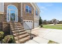 Exterior shot of the home with stone steps leading to the arched front door, along with a two-car garage at 7235 Magnolia Ln, Fairburn, GA 30213