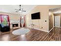 Cozy living room featuring wood flooring, a fireplace, a ceiling fan, and natural light at 7235 Magnolia Ln, Fairburn, GA 30213