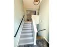 View of a carpeted staircase with modern gray paint and black handrails, leading to the upper level of the home at 226 Saul Dr, Ellenwood, GA 30294