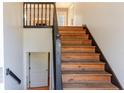 Staircase with wooden steps, dark railing, and a view of the lower level and an upstairs window at 1004 Hamilton Dr, Locust Grove, GA 30248