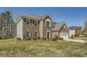 Side view of a two-story brick home featuring red shutters, manicured lawn, and an attached garage at 4157 Medlock Woods Dr, Snellville, GA 30039