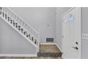 Bright foyer with a staircase featuring white railings and carpeted steps at 5724 Antelope Trl, Atlanta, GA 30349