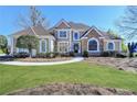 Beautifully landscaped home featuring lush lawn, an arched entryway, and manicured bushes at 7910 St Marlo Country Club Pkwy, Duluth, GA 30097