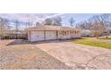 Single-story home features a two-car garage with a long driveway and cozy front porch at 1408 Lake Paradise Rd, Villa Rica, GA 30180