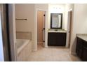 Bathroom featuring double granite vanity, soaking tub with tile surround, and access to closet at 651 Deer Springs Way, Loganville, GA 30052