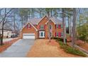 Charming two-story brick home with red shutters, mature trees, and a driveway leading to a two-car garage at 386 Coopers Pond Dr, Lawrenceville, GA 30044