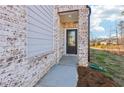 Inviting entrance to a two-story townhome boasts a glass paneled door, brick facade, and concrete entryway at 552 Pennsy Aly, Mableton, GA 30126