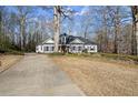 Picturesque single-story home with a long driveway, lush lawn, and mature trees, creating a private oasis at 6170 Wellington Ct, Cumming, GA 30040