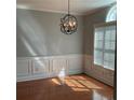Elegant dining room featuring hardwood floors, a modern light fixture, wainscoting, and a window at 5027 Bayrose Cir # 27A, Atlanta, GA 30344
