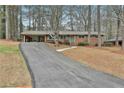 Long driveway to a brick ranch-style home with blue shutters and covered carport in a wooded setting at 2941 Pine Valley Cir, East Point, GA 30344