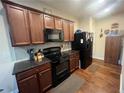 Charming kitchen featuring sleek black appliances, granite countertops, and wooden cabinetry with ample storage space at 1426 Brookmere Way, Cumming, GA 30040