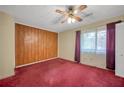 Bedroom with wood paneling, ceiling fan, window and red carpet at 2570 Bradford Ne Sq, Atlanta, GA 30345