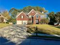 Beautiful two-story red brick home with a manicured lawn, a two-car garage, and mature trees at 3381 Walkers Ridge Rd, Dacula, GA 30019