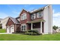 A two-story brick home featuring a manicured lawn and an attached two-car garage at 5792 Village Loop, Fairburn, GA 30213