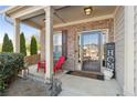 Inviting front porch with a red chair, decorative sign, and well-maintained landscaping at 149 Manor Lane, Woodstock, GA 30188