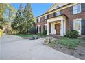 Charming brick home featuring black shutters, white columns, and lush landscaping at 3000 Rivermeade Nw Dr, Atlanta, GA 30327