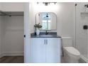 Modern bathroom featuring a sleek vanity with a black countertop, mirror, toilet, and tiled shower at 158 Palisade Dr, Rydal, GA 30171