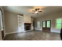 Spacious living room featuring a stone fireplace, built-in bookshelves, stylish ceiling fan and wood-look floors at 554 Presley Farm Parkway, Rockmart, GA 30153