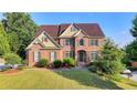 Charming brick two-story home featuring a lush green lawn and established landscaping at 1755 Riverpark Dr, Dacula, GA 30019
