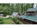 Exterior of a charming rustic home with a metal roof, featuring a covered carport and a verdant, tree-filled yard at 6245 Bannister Rd, Cumming, GA 30028